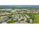 Expansive aerial view of community with lake, surrounded by lush greenery and urban infrastructure at 1207 Pine Ridge W Cir # H2, Tarpon Springs, FL 34688