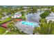 Aerial view of community pool, lake with fountain, tennis courts, and lush landscaping at 1207 Pine Ridge W Cir # H2, Tarpon Springs, FL 34688