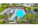 Aerial view of community pool and tennis courts with blue umbrellas and palm trees at 1207 Pine Ridge W Cir # H2, Tarpon Springs, FL 34688