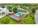 Aerial view of community pool, lake, tennis courts, and surrounding residential neighborhood at 1207 Pine Ridge W Cir # H2, Tarpon Springs, FL 34688
