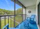 Relaxing screened balcony with blue rocking chairs and table overlooking a grassy outdoor area at 1207 Pine Ridge W Cir # H2, Tarpon Springs, FL 34688