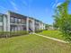 Exterior view of a light colored condo with lush green landscaping and a sidewalk at 1207 Pine Ridge W Cir # H2, Tarpon Springs, FL 34688