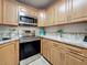 The kitchen has stainless steel appliances, gray countertops, and light wood cabinets at 1207 Pine Ridge W Cir # H2, Tarpon Springs, FL 34688