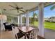The sunroom features a ceiling fan, comfortable seating, and gorgeous views of the lawn and pond at 123 Glendower Cir # 123, Sun City Center, FL 33573