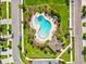 Aerial view of the sparkling community pool, surrounded by lounge chairs, tropical landscaping, and green space at 1325 Custer Bayou St, Ruskin, FL 33570