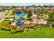 Blue playground equipment with shade and swings surrounded by lush landscaping in a Gathering-friendly community at 1325 Custer Bayou St, Ruskin, FL 33570