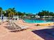 Inviting community pool area with lounge chairs and mature trees, creating a serene and relaxing atmosphere at 14230 86Th Ter, Seminole, FL 33776