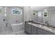 Elegant bathroom with a soaking tub behind glass, a double vanity, and marble-look tile at 14422 Chamberlain Blvd, Port Charlotte, FL 33953