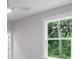 Bright bedroom featuring a ceiling fan and a window showcasing a lush, green outdoor view at 14422 Chamberlain Blvd, Port Charlotte, FL 33953