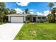 Charming single-story home features a well-manicured lawn, paved driveway, and an attached two-car garage at 14422 Chamberlain Blvd, Port Charlotte, FL 33953