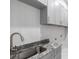 Functional laundry area with granite counters, gray cabinets, and a stainless steel sink at 14422 Chamberlain Blvd, Port Charlotte, FL 33953