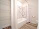 Bathroom featuring tub shower with marble-patterned walls and wood-look flooring at 1536 Palmetto St, Clearwater, FL 33755