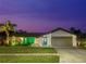 Charming single-story home featuring a well-manicured lawn, lush landscaping, and a striking teal front door at twilight at 1632 Ridge Top Way, Clearwater, FL 33765
