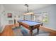 Spacious game room with a blue felt pool table, hardwood floors, natural light and elegant chandelier above the billiards table at 1632 Ridge Top Way, Clearwater, FL 33765