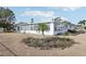 Exterior view of home with a well-maintained gravel yard, landscaping, and a peek at the screened-in patio at 1732 Flamingo Ln, Sun City Center, FL 33573