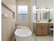 Bright bathroom featuring vanity with makeup station, complemented by a sleek, freestanding soaking tub at 1800 Loch Haven Ct, Trinity, FL 34655