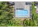 Aerial view of a screened-in pool with lush greenery and serene, clear blue water at 1800 Loch Haven Ct, Trinity, FL 34655