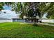 The backyard features mature trees providing shade and a firepit. The yard is surrounded by a fence at 1800 Pine St, Clearwater, FL 33764
