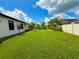 A large backyard with lush green grass, palm trees, a putting green, and a well-maintained fence at 31889 Tortuga Shore Loop, Wesley Chapel, FL 33545