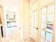 Hallway leading to a kitchen with white cabinets and stainless steel appliances, and a view through glass paneled doors at 31889 Tortuga Shore Loop, Wesley Chapel, FL 33545