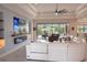 Bright living room featuring a modern fireplace, large television and access to the outdoor pool area at 31889 Tortuga Shore Loop, Wesley Chapel, FL 33545