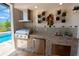 Outdoor kitchen with stainless steel grill, mosaic tile backsplash, stone counter, and built-in refrigerator at 31889 Tortuga Shore Loop, Wesley Chapel, FL 33545