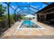 Screened-in pool with lounge chairs, umbrella, and outdoor kitchen in luxurious backyard setting at 31889 Tortuga Shore Loop, Wesley Chapel, FL 33545