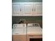 Bright laundry room featuring front load washer and dryer with white cabinets above at 3665 Country Pointe Pl, Palm Harbor, FL 34684