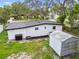 Backyard view of the home featuring a small shed, and lush greenery at 4220 E Regnas Ave, Tampa, FL 33617