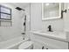 Updated bathroom featuring marble-style tile, modern fixtures, a bathtub, and a vanity with an illuminated mirror at 4220 E Regnas Ave, Tampa, FL 33617