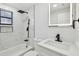 Updated bathroom featuring marble-style tile, modern fixtures, a bathtub, and a vanity with an illuminated mirror at 4220 E Regnas Ave, Tampa, FL 33617