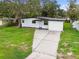 Charming home exterior featuring mature trees, a well-kept lawn, and a paved driveway at 4220 E Regnas Ave, Tampa, FL 33617