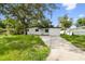A well maintained front exterior featuring a driveway and a mature tree at 4220 E Regnas Ave, Tampa, FL 33617