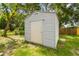 Backyard shed on a grassy lot with an access door and green landscape at 4220 E Regnas Ave, Tampa, FL 33617
