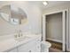 Bright bathroom with a white vanity, a circular mirror, and an open closet featuring wood-look floors at 4503 Jacona Dr, Hernando Beach, FL 34607
