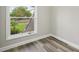 Bright bedroom corner featuring gray walls, white trim, wood-look floors, and a view of the landscape at 4503 Jacona Dr, Hernando Beach, FL 34607