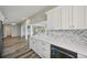 Open concept kitchen with white cabinets, modern backsplash, and stainless steel dishwasher at 4503 Jacona Dr, Hernando Beach, FL 34607