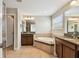 Bathroom with a soaking tub, granite countertops, a dual sink vanity, and a separate door for added privacy at 4544 Vermillion Sky Dr, Wesley Chapel, FL 33544