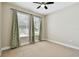 Bright bedroom featuring tile flooring, ceiling fan, neutral walls, and two windows with decorative curtains at 4544 Vermillion Sky Dr, Wesley Chapel, FL 33544