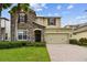Charming home featuring a stone facade, well-manicured lawn, and a brick paved driveway leading to a two-car garage at 4544 Vermillion Sky Dr, Wesley Chapel, FL 33544