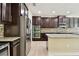 Kitchen with stainless steel refrigerator, dual ovens, granite counters, tile backsplash and dark wood cabinetry at 4544 Vermillion Sky Dr, Wesley Chapel, FL 33544