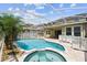 Resort-style screened-in pool and spa surrounded by a paved patio and tropical landscaping at 4544 Vermillion Sky Dr, Wesley Chapel, FL 33544