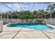 Screened-in pool with waterfall feature and travertine tile decking at 4544 Vermillion Sky Dr, Wesley Chapel, FL 33544