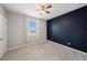 Modern bedroom featuring carpet, a ceiling fan, a window, and a dark blue accent wall at 5027 Autumn Ridge Dr, Wesley Chapel, FL 33545