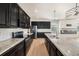 Modern kitchen boasts granite counters, black cabinetry, stainless appliances, herringbone backsplash, and hardwood floors at 5027 Autumn Ridge Dr, Wesley Chapel, FL 33545