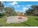 Backyard with brick-paved patio and fire pit, surrounded by lush lawn and beautiful trees at 512 Crystal Grove Blvd, Lutz, FL 33548