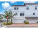 Front view of a three-story townhome with a two-car garage, brick pavers, and lush landscaping at 5351 Bridge St # 16, Tampa, FL 33611