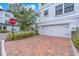View of garage with brick paved driveway, white exterior and nicely manicured lawn at 5351 Bridge St # 16, Tampa, FL 33611