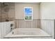 Luxurious soaking tub with wooden tile surround and showerhead at 6707 Josie Dr, Seffner, FL 33584