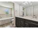 Bathroom with double sink vanity, a large mirror, and a bathtub with tile surround at 6707 Josie Dr, Seffner, FL 33584